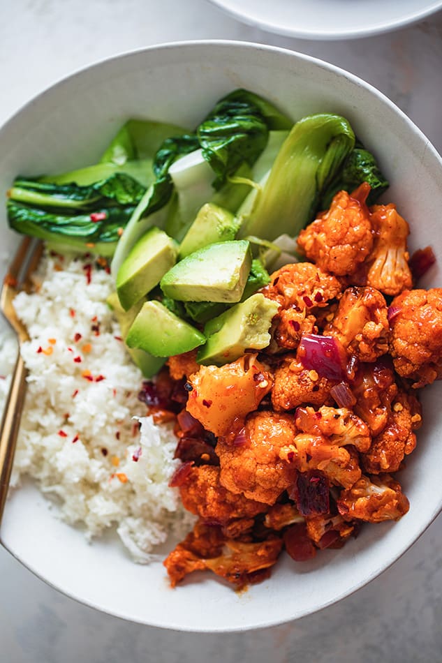 Overhead view of a bowl of Orange Cauliflower with bok choy and white rice