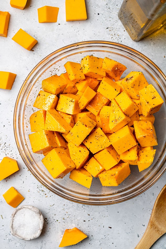 Top view of raw butternut squash in a mixing bowl with oil