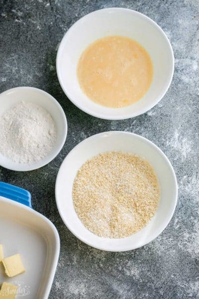 Three White Bowls Containing the Breading Mixture, the Marinade and the Almond Flour