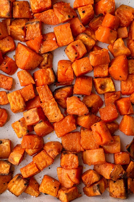 Cubed roasted sweet potatoes on a rectangle baking sheet