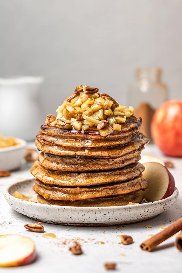 Side view of apple pancakes topped with chopped apples and pecans