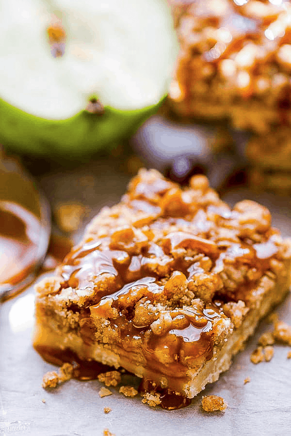Top view of one vegan apple pie bar on a cutting board with paleo caramel sauce drizzled on top