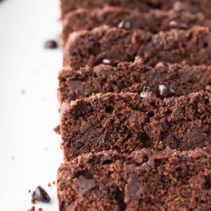 Close-up top view of five slices of chocolate zucchini bread on a white plate