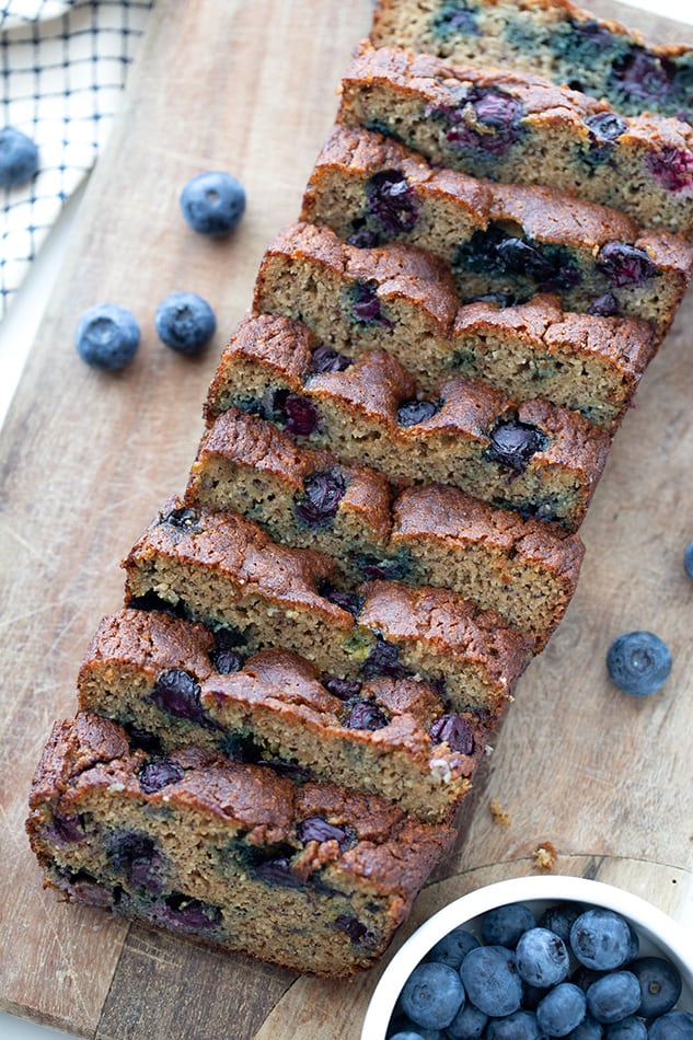 Top view of sliced blueberry banana bread on wooden cutting board.