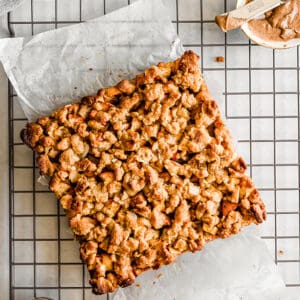 Top view of uncut peach crumb bars on parchment paper on a white background