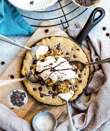 Top view of skillet cookie in a cast iron pan with dairy-free ice cream and a spoon