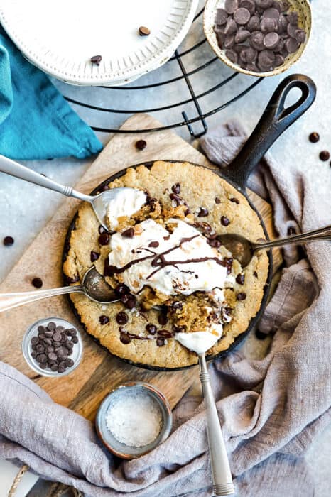 Top view of skillet cookie in a cast iron pan with dairy-free ice cream and a spoon