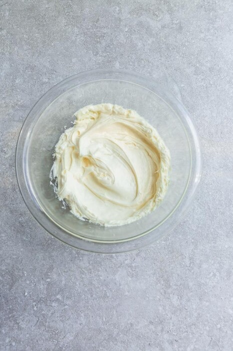 Dairy-free cream cheese frosting inside of a glass bowl on a granite surface