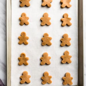 Top view of 15 cut-out keto gingerbread cookie dough on a baking sheet