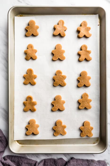 Top view of 15 cut-out keto gingerbread cookie dough on a baking sheet