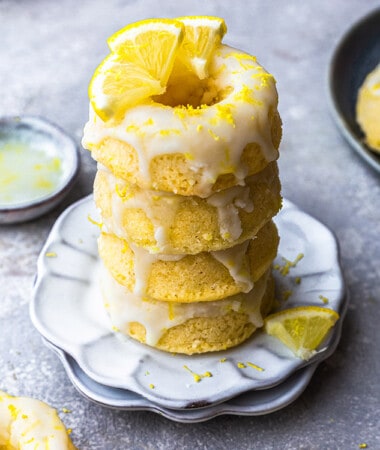 Side shot of a stack of four lemon donuts on a plate