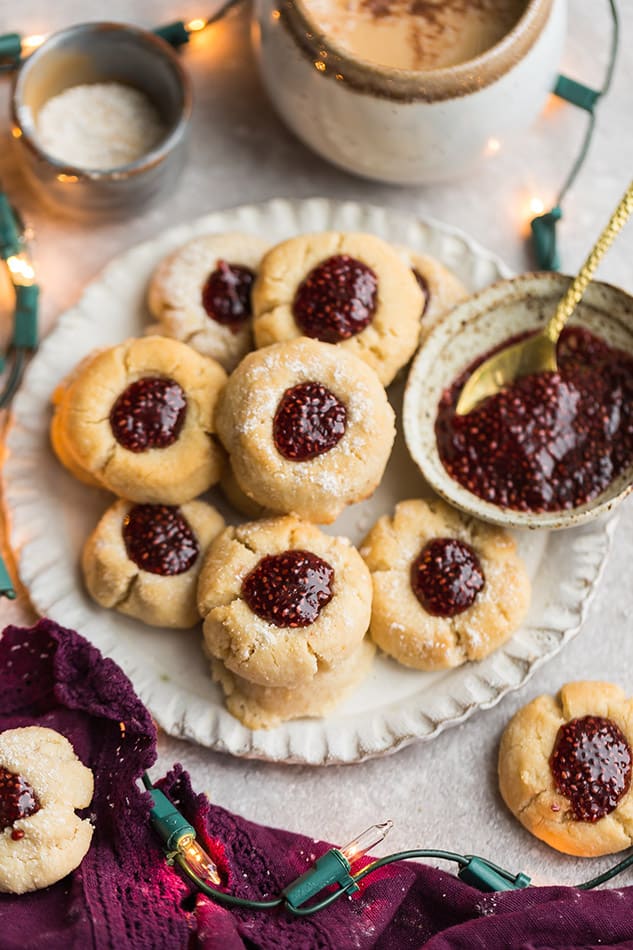 Top side view of keto thumbprint cookies on a white plate with strawberry chia jam