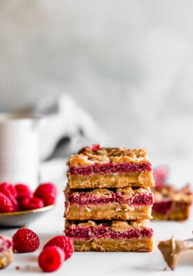 Side view of three raspberry crumb bars stacked on a white background