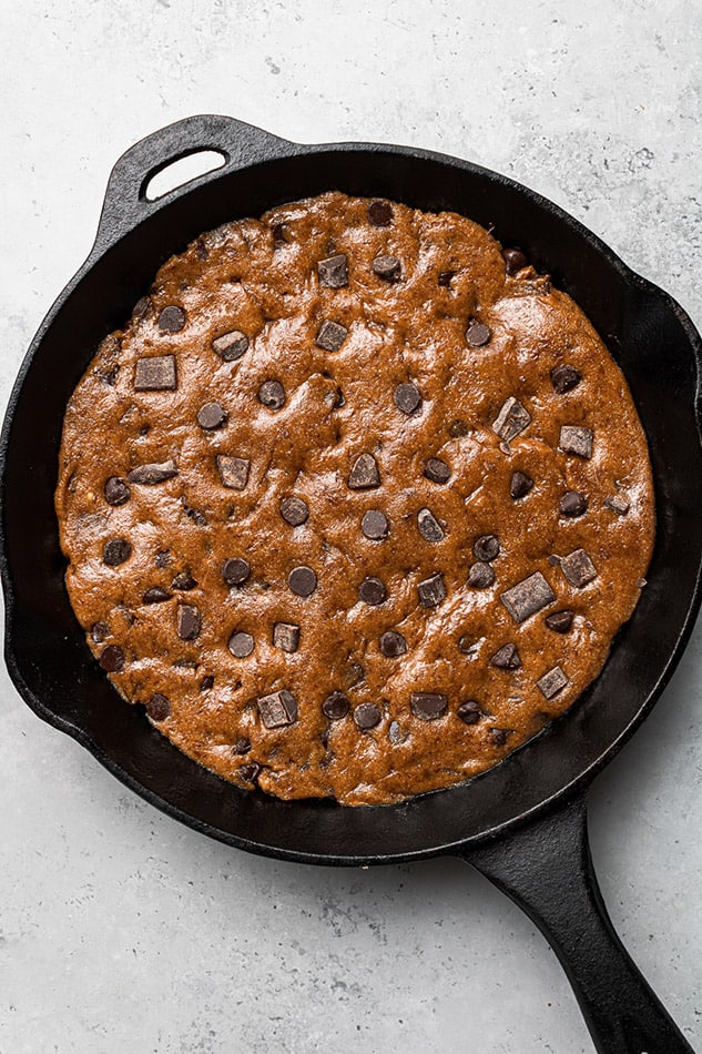 A cast-iron skillet with chocolate chip cookie dough pressed inside