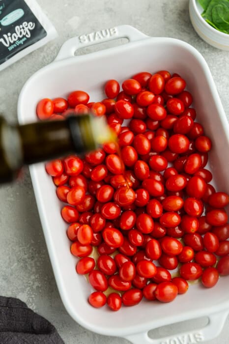 Cherry tomatoes in a white casserole dish drizzled with olive oil