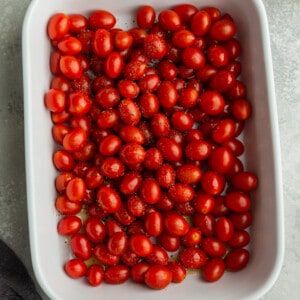 Cherry tomatoes in a white casserole dish drizzled with olive oil
