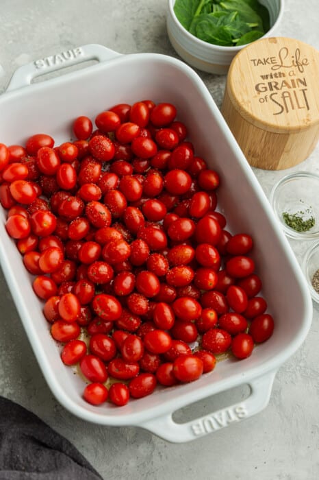 Cherry tomatoes in a white casserole dish with salt and pepper