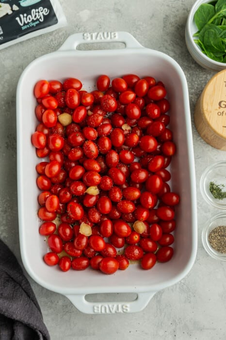 Cherry tomatoes in a white casserole dish with garlic