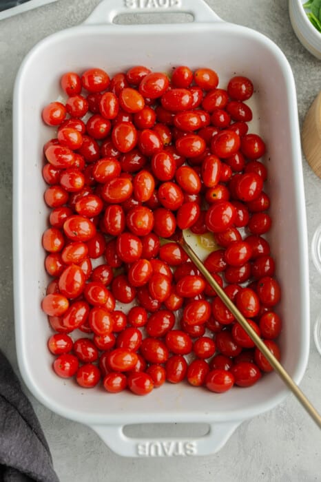Cherry tomatoes in a white casserole dish with a spoon