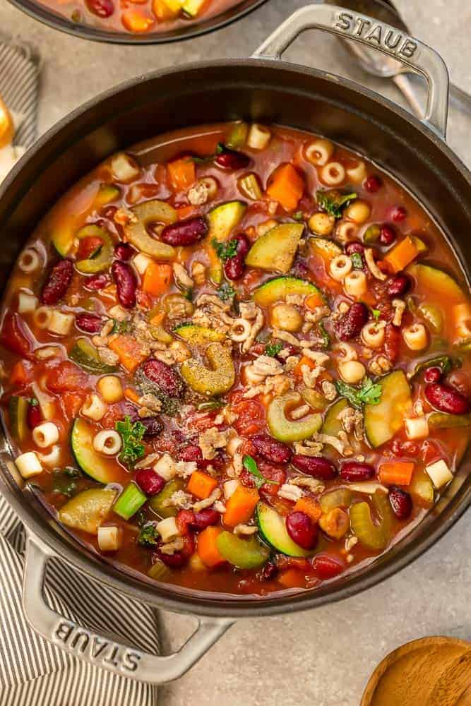 Close-up of a batch of Pasta E Fagioli Soup in a grey cast iron dutch-oven pot on a grey background.