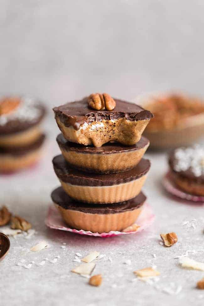 A stack of homemade nut butter chocolate cups topped with a pecan