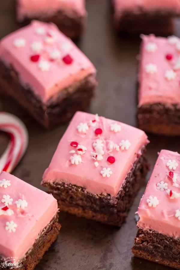 Overhead view of pink frosted peppermint brownies topped with snowflake sprinkles