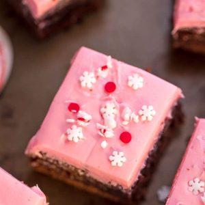Overhead view of pink frosted peppermint brownies topped with snowflake sprinkles