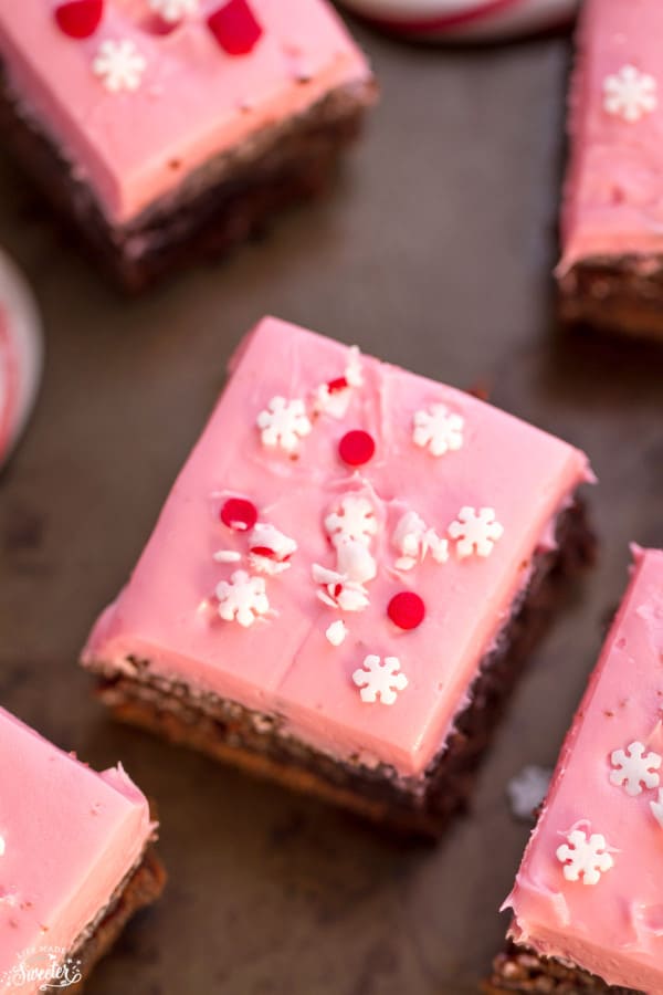 Overhead view of pink frosted peppermint brownies topped with snowflake sprinkles