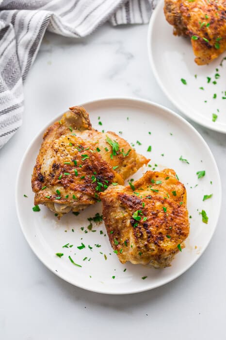 Two air fryer chicken thighs on a white plate