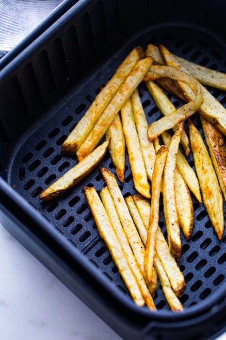 A batch of cooked french fries in an air fryer basket