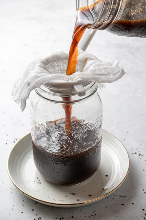 Homemade coffee being steeped through a mesh sieve lined with a cheesecloth