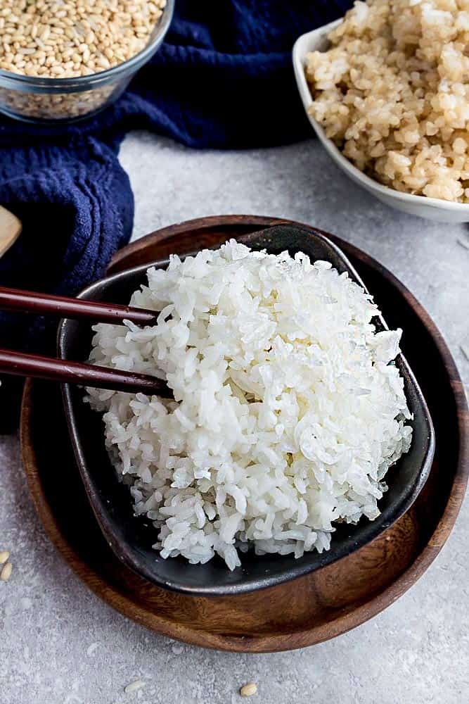 A Pair of Chopsticks Digging Into a Bowl of White Rice