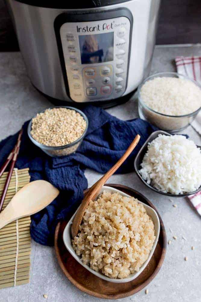 Bowls of White and Brown Rice on a Counter with Cloth Napkins and Wooden Spoons