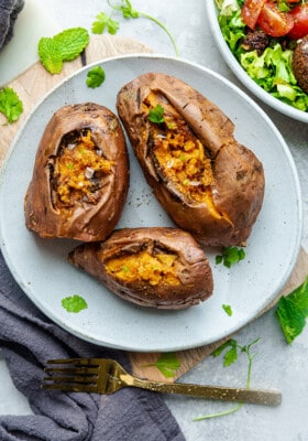 Three Instant Pot baked sweet potatoes with parsley on a white plate