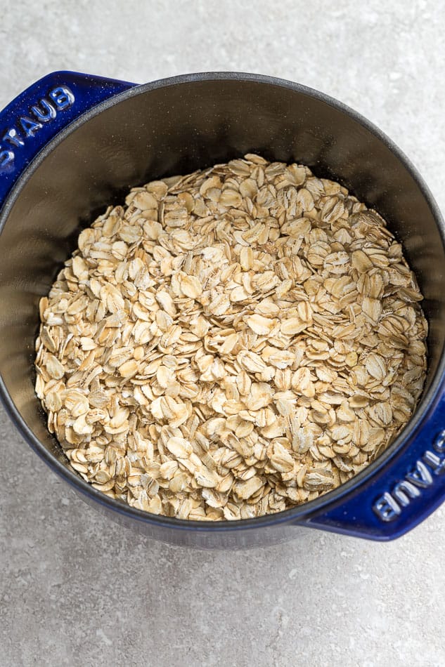 Top view of old fashioned rolled oats in a blue pot on a grey background
