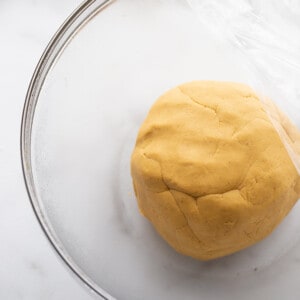 Top view of pumpkin cinnamon roll dough in a clear bowl