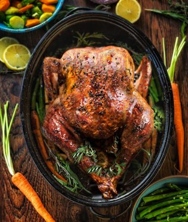 Top view of a perfectly golden brown turkey in a pan with side dishes