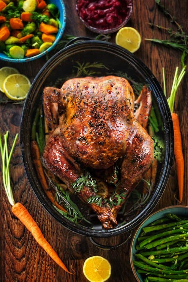 Top view of a perfectly golden brown turkey in a pan with side dishes