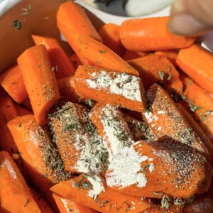 Raw carrot slices in a white mixing bowl with seasonings
