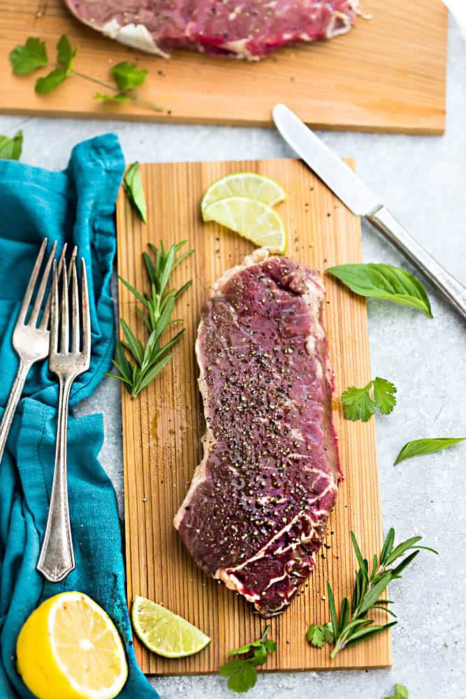 Top view of a raw steak with dry rub on a cutting board