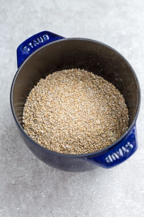 Top view of steel cut oats in a blue pot on a grey background