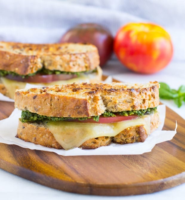 Spinach Basil Pesto and tomato grilled cheese sandwiches on a wooden board