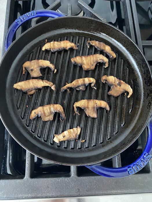 Cooked portobello mushroom slices on blue grill pan