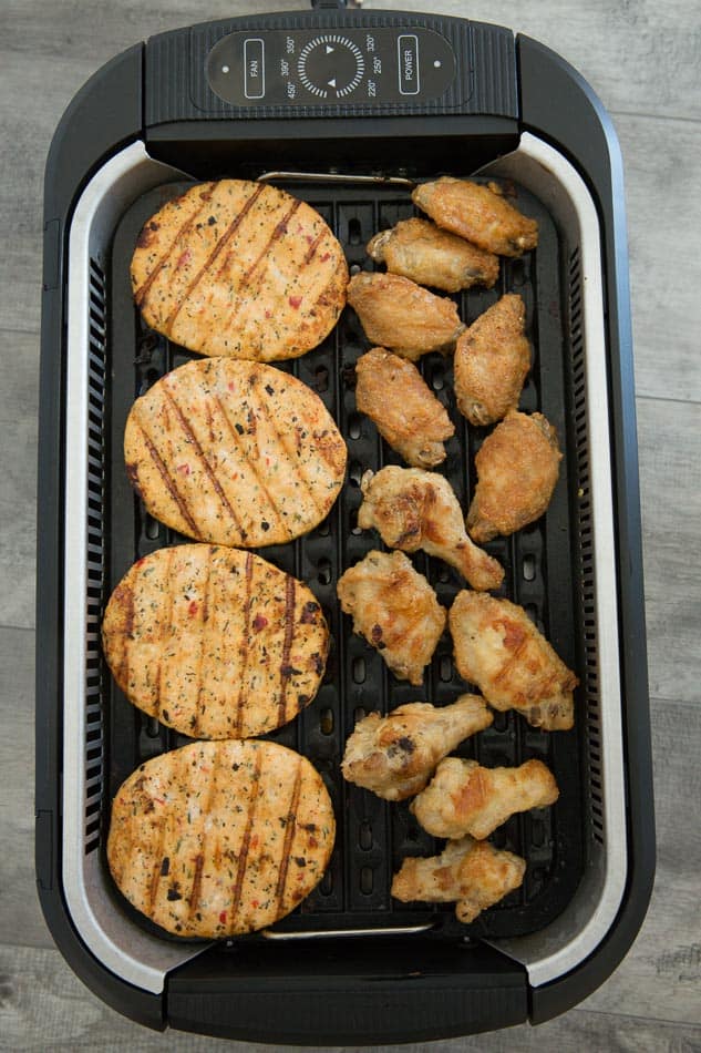 Overhead view of chicken burgers and wings in a Power Smokeless Grill