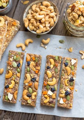 Top view of four pumpkin oatmeal bars with dried blueberries on a parchment paper