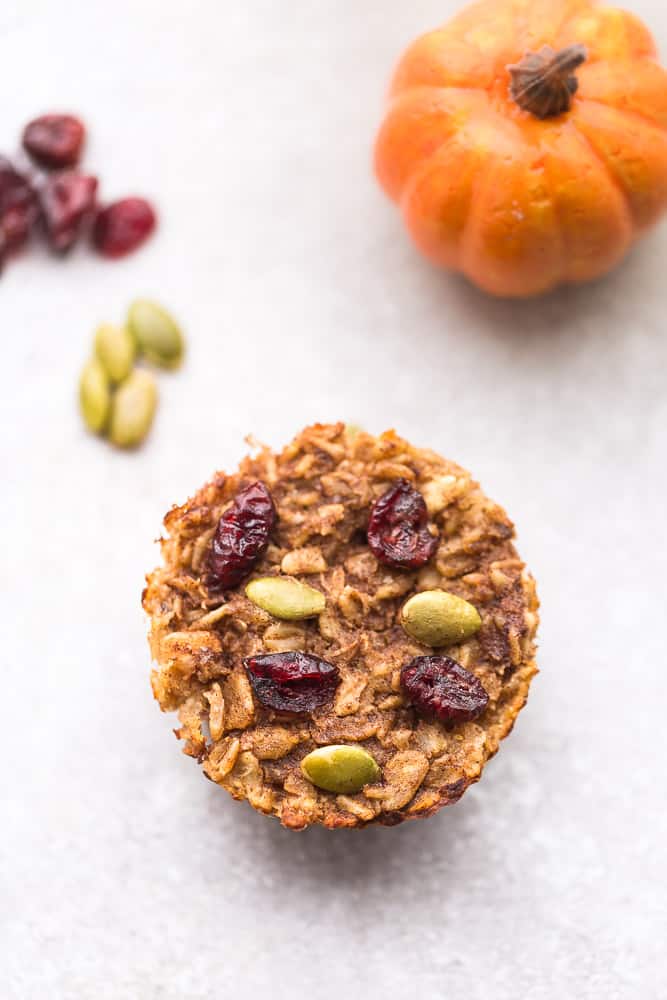PUMPKIN CRANBERRY oatmeal cup with raisins and a pumpkin on the side.