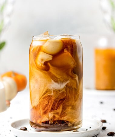 Side angle of one iced pumpkin cold brew coffee in a glass