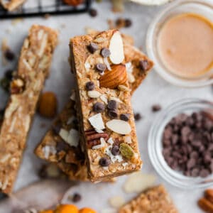 Close up top view of stacked pumpkin granola bars with chocolate chips on a grey background