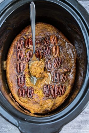 An entire baked pumpkin pecan cake in a black slow cooker