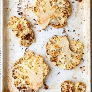 5 slices of roasted cauliflower steaks on a baking sheet